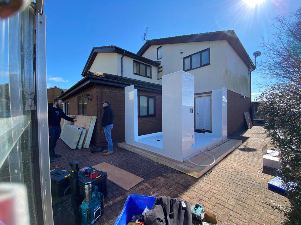 Photo showing the half erected external WashPod temporary disabled wetroom being built on the driveway of a house.