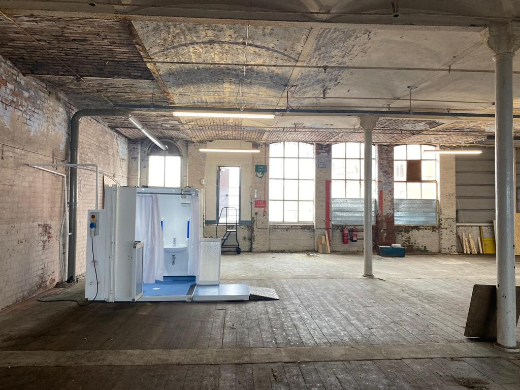 Photo showing a Micro WashPod in a large space of a former cotton mill
