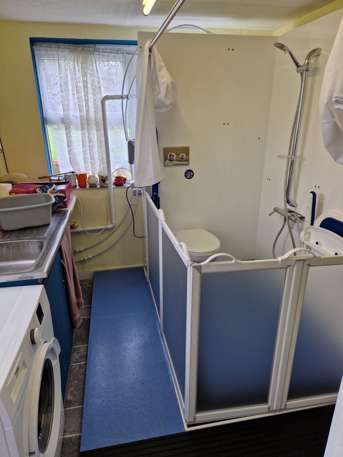 Photo showing how the new Mini WashPod temporary disabled wetroom with shower and toilet can fit into a small utility room to give accessible washing.